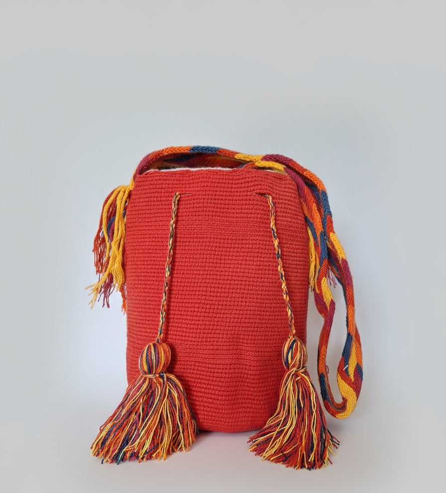 Detailed view of traditional Wayuu crochet technique and tassels on a red mochila bag. Ethically and responsibly sourced.
