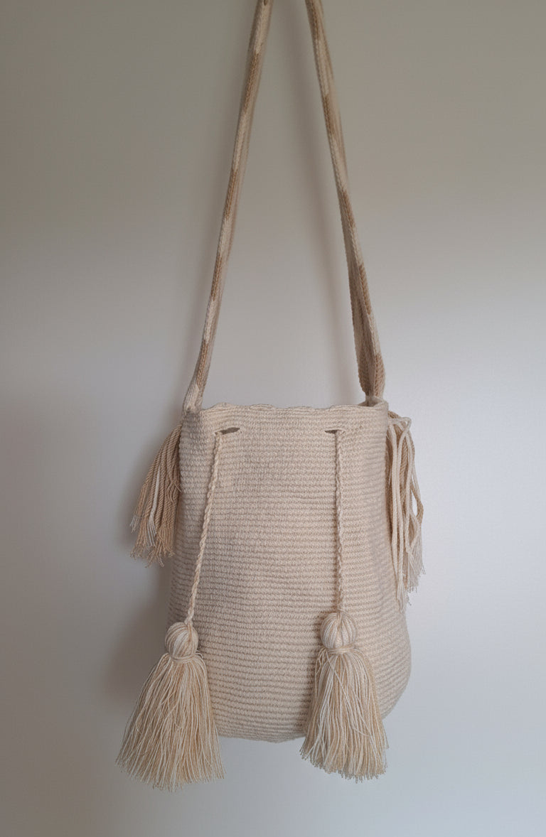 Detailed view of traditional Wayuu crochet technique in light beige with tassels and crossbody strap fully extended. Mochila bag is artisan-made and perfect for boho styling.