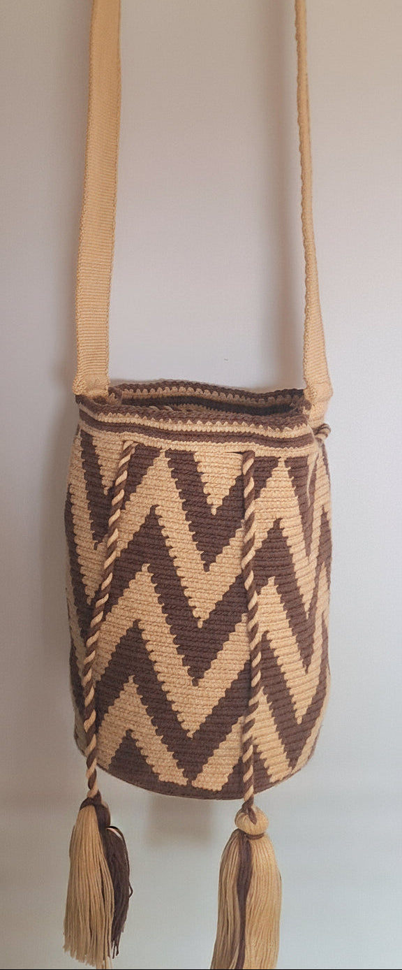 Detailed view of medium wayuu bag with bold zigzag design in beige and brown, with crossbody strap fully extended. Bag is responsibly hand-crafted; a boho festival essential.