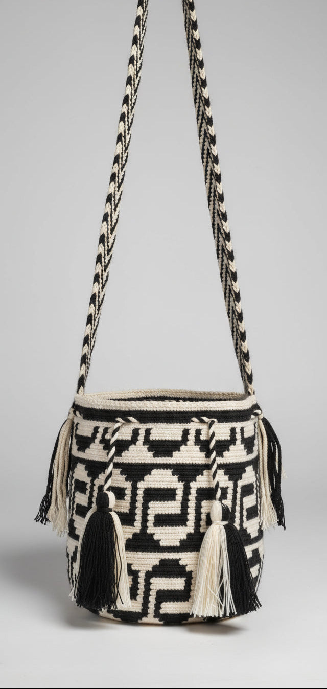 Detailed view of traditional medium-sized Wayuu Mochila in black and white serpentine pattern with tassels and crossbody strap fully extended. Bag supports indigenous weavers with every boho purchase.
