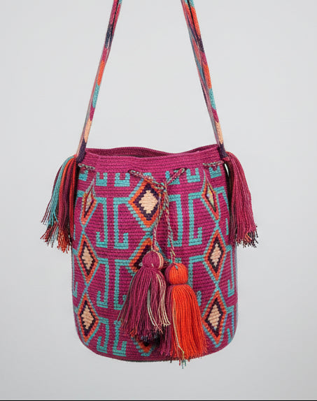 Detailed view of traditional Wayuu crochet technique and tassels on a mochila bag in pink and blue. Ethically and responsibly sourced.