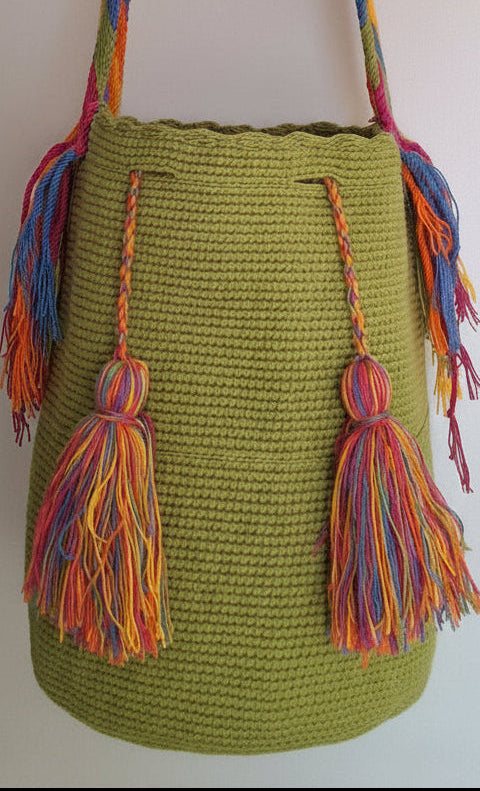 Detailed view of traditional Wayuu crochet technique in green threads and tassels. Large mochila bag is sustainably sourced and styled for boho summer days.