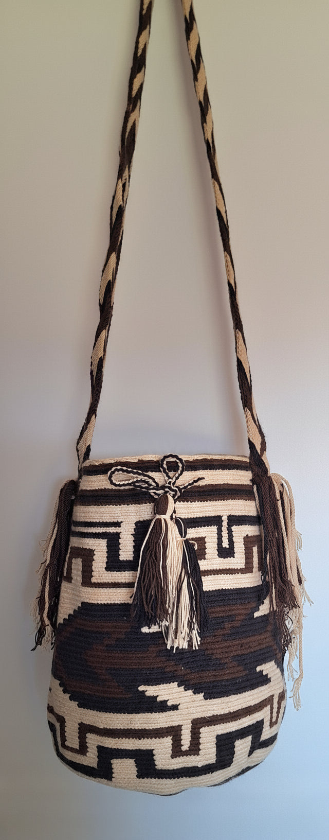 Detailed view of traditional Wayuu crochet technique and tassels on a brown and beige mochila bag with crossbody strap fully extended. Ethically and responsibly sourced.
