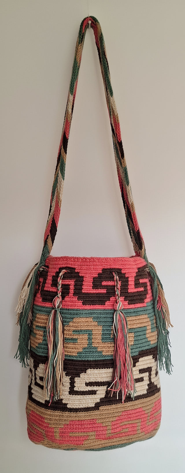 Detailed view of traditional Wayuu crochet technique and tassels on a mochila bag with serpentine design symbol for wisdom and crossbody strap fully extended. Ethically and responsibly sourced.