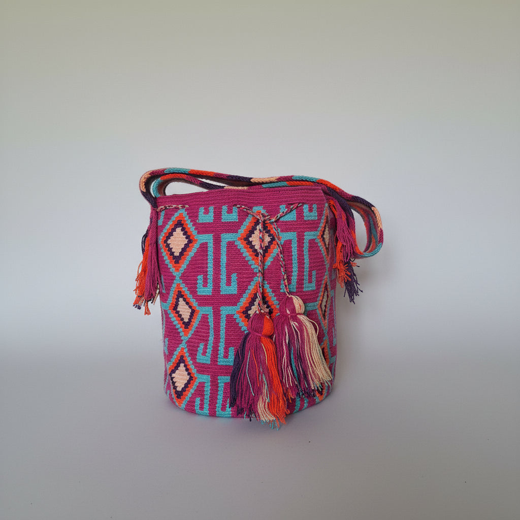 Detailed view of traditional Wayuu crochet technique and tassels on a mochila bag in pink and blue. Ethically and responsibly sourced.