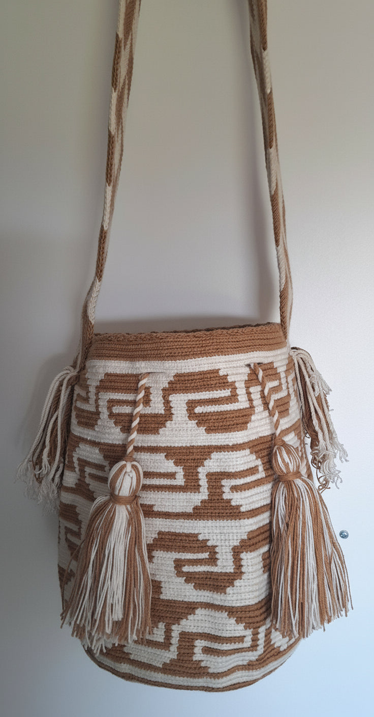 Detailed view of traditional Wayuu crochet technique and tassels on a beige and white mochila bag with crossbody strap fully extended. Ethically and responsibly sourced.