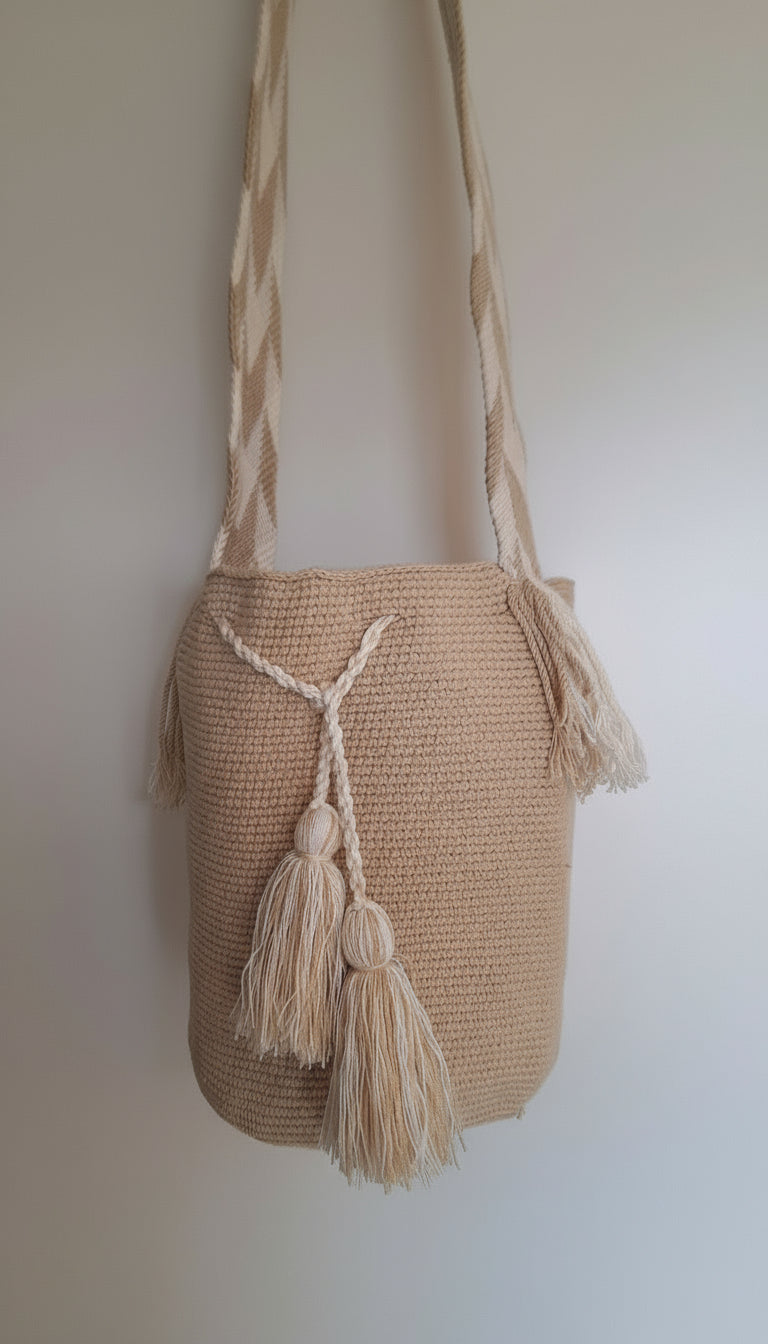 Detailed view of traditional Wayuu crochet technique in fawn beige with tassels and crossbody strap fully extended. Large mochila bag is  hand-woven by artisans; great for boho-chic layers.
