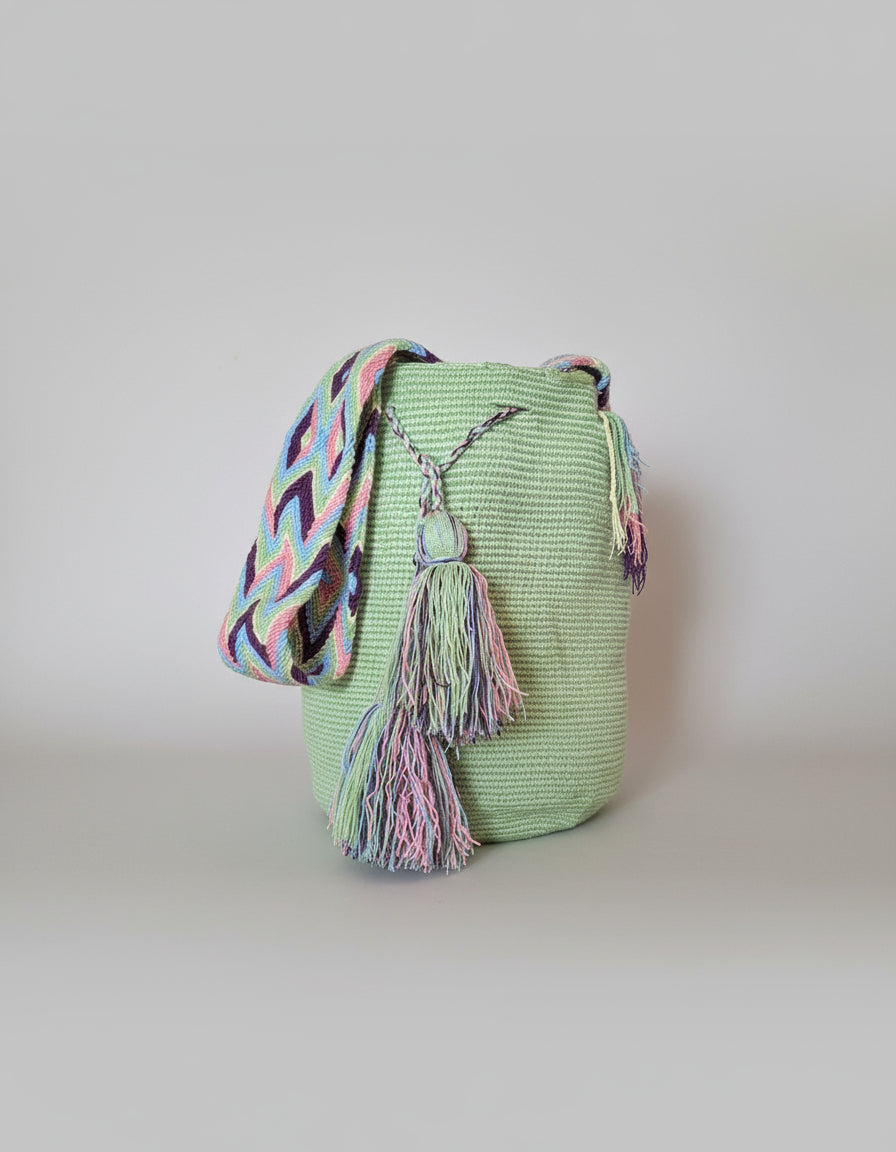 Authentic handmade Colombian Wayuu Mochila in lime green cotton threads with colorful tassels and strap. Bag is sustainably sourced and styled for boho summer days.