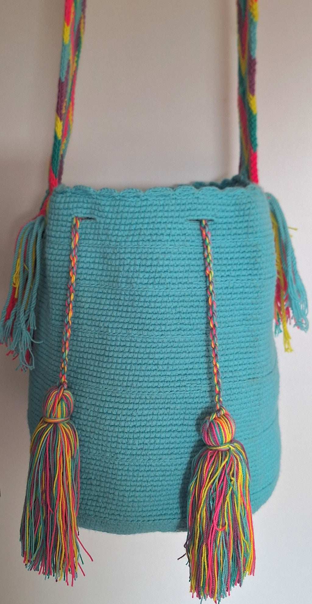 Detailed view of traditional Wayuu crochet technique in turquoise green with tassels and crossbody strap fully extended. Large mochila bag is ethically sourced for a conscious boho wardrobe.
