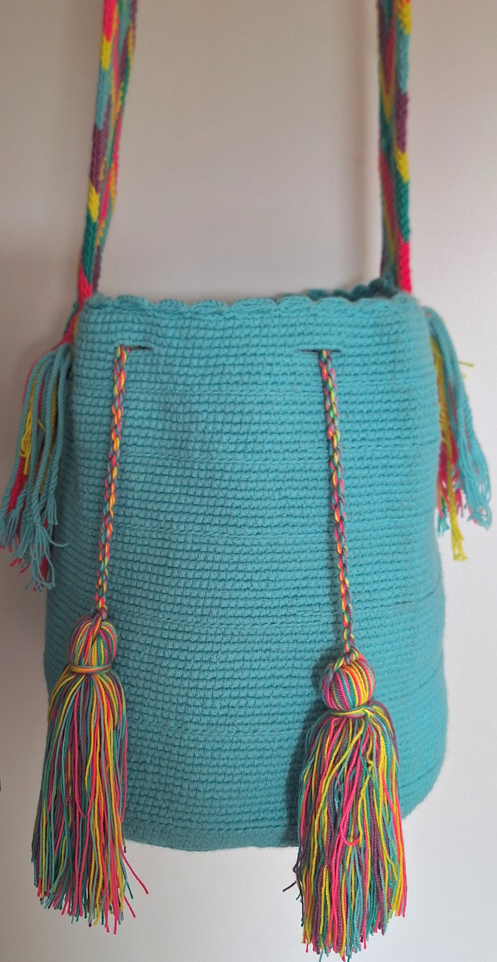 Detailed view of traditional Wayuu crochet technique in turquoise green with tassels and crossbody strap fully extended. Large mochila bag is ethically sourced for a conscious boho wardrobe.