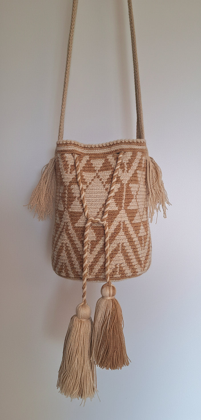 Detailed view of traditional Wayuu crochet technique in cream and beige with solar design and tassels with crossbody strap fully extended. Mochila bag is hand-woven by artisans; great for boho-chic layers.