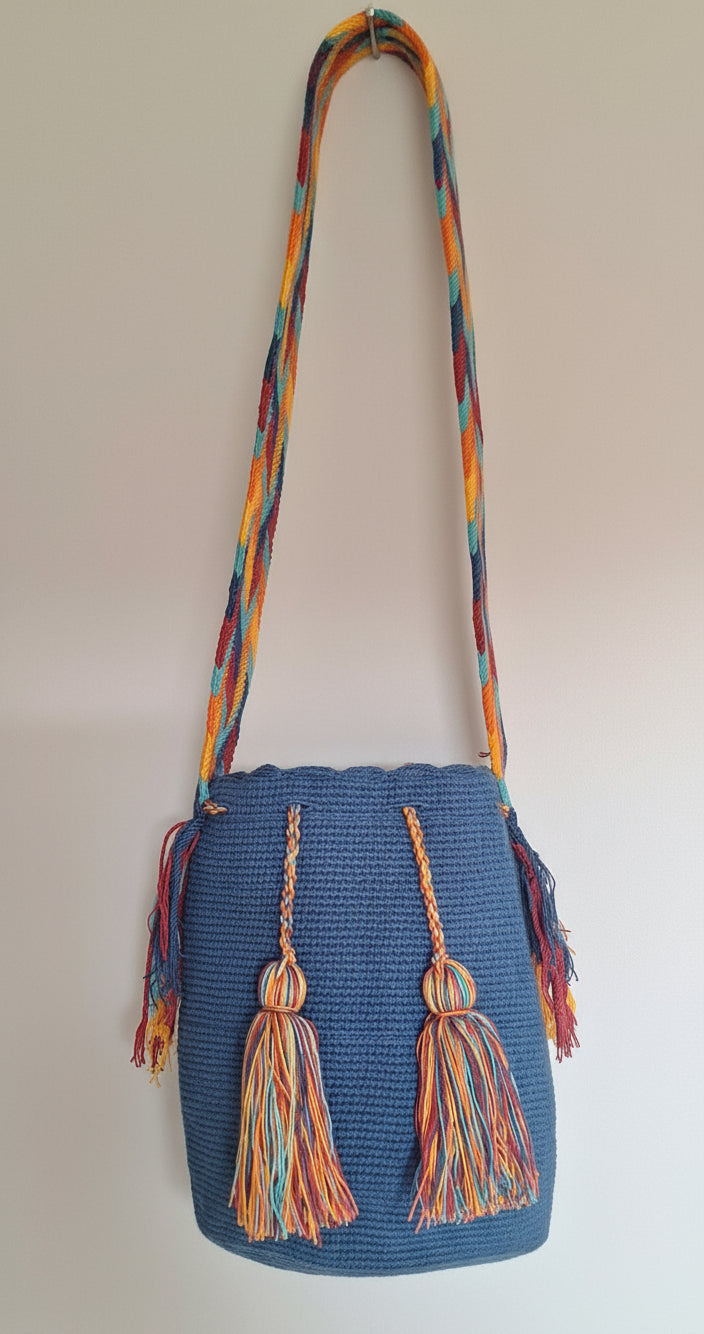 Detailed view of traditional Wayuu bag, navy blue with colourful tassels and crossbody strap fully extended. Bag is artisan-made and perfect for boho styling.