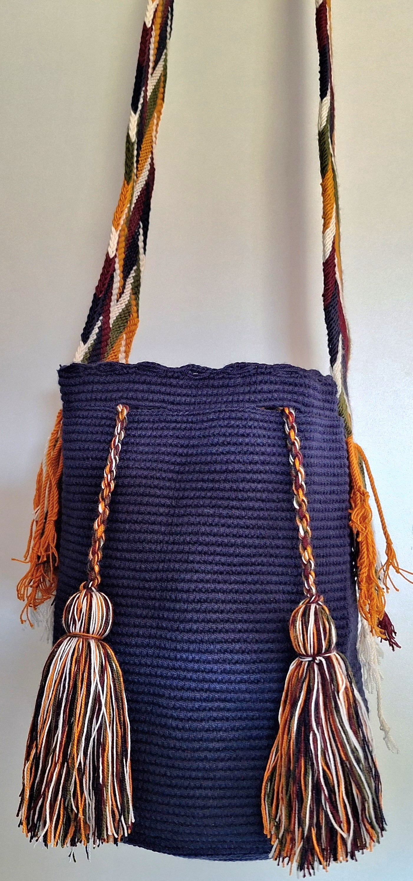 Detailed view of traditional Wayuu crochet technique and tassels on a dark blue mochila bag with crossbody strap fully extended. Ethically and responsibly sourced.