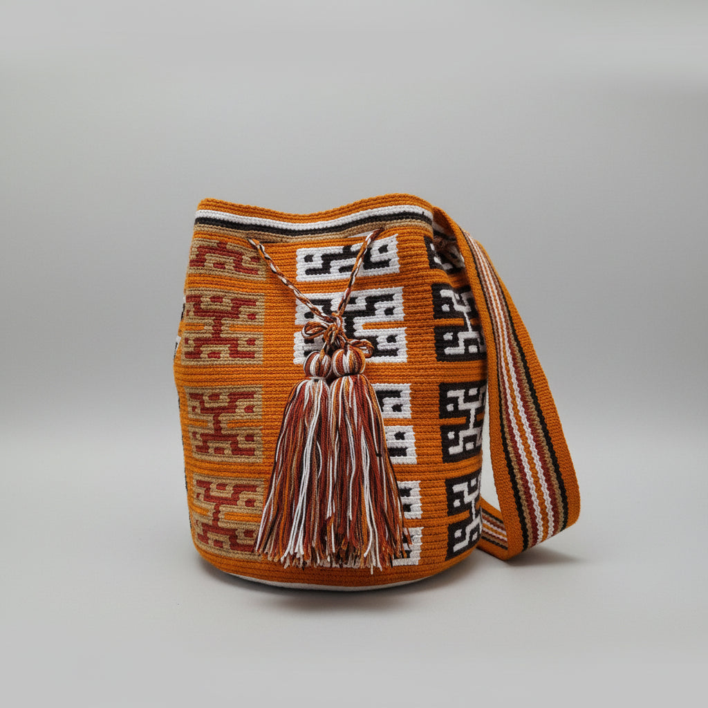 A handwoven Wayuu mochila bag in vibrant ochre, black, white, and red, displayed on a a plain light background. Traditional design and matching strap, make this bag a great gift for ethical buyers.