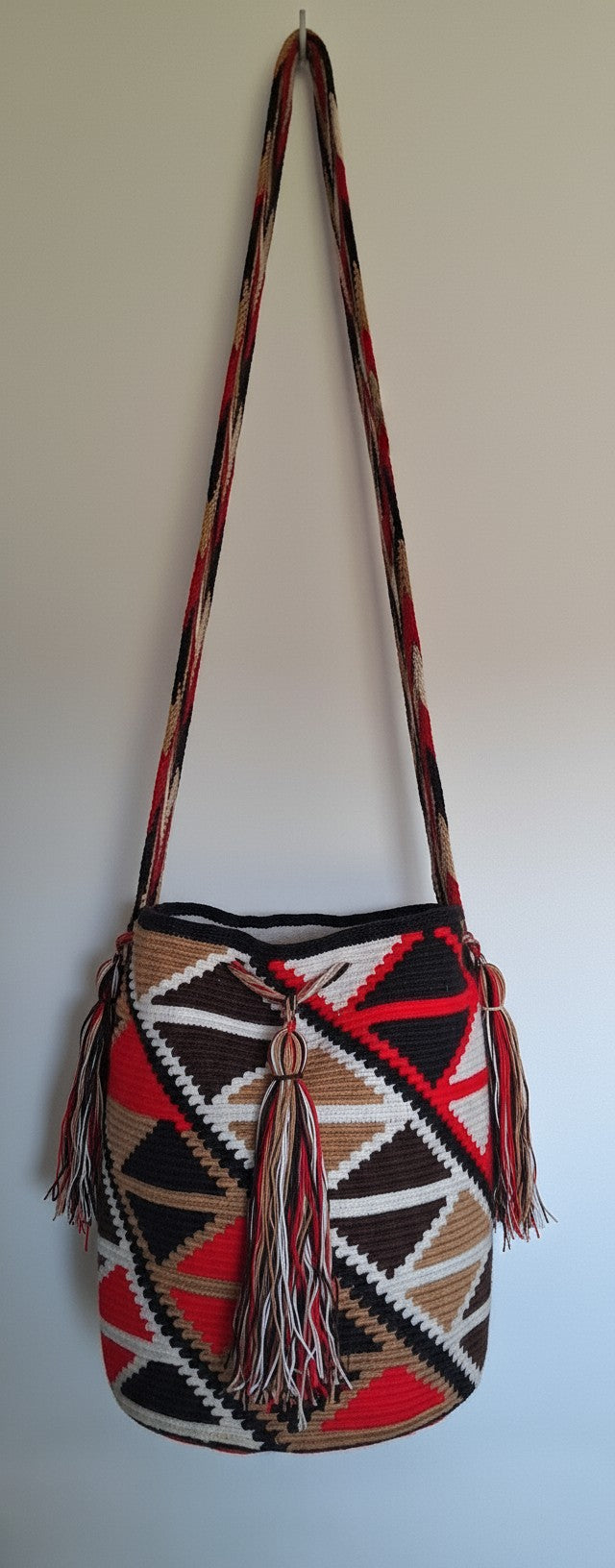 Detailed view of traditional Wayuu crochet technique with diamond design and tassels on a mochila bag with crossbody strap fully extended. Ethically and responsibly sourced.