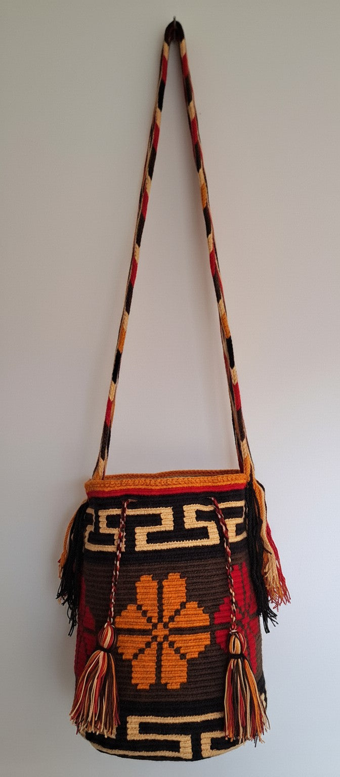 Detailed view of traditional Wayuu crochet technique and tassels on a mochila bag with four petal design and crossbody strap fully extended. Ethically and responsibly sourced.