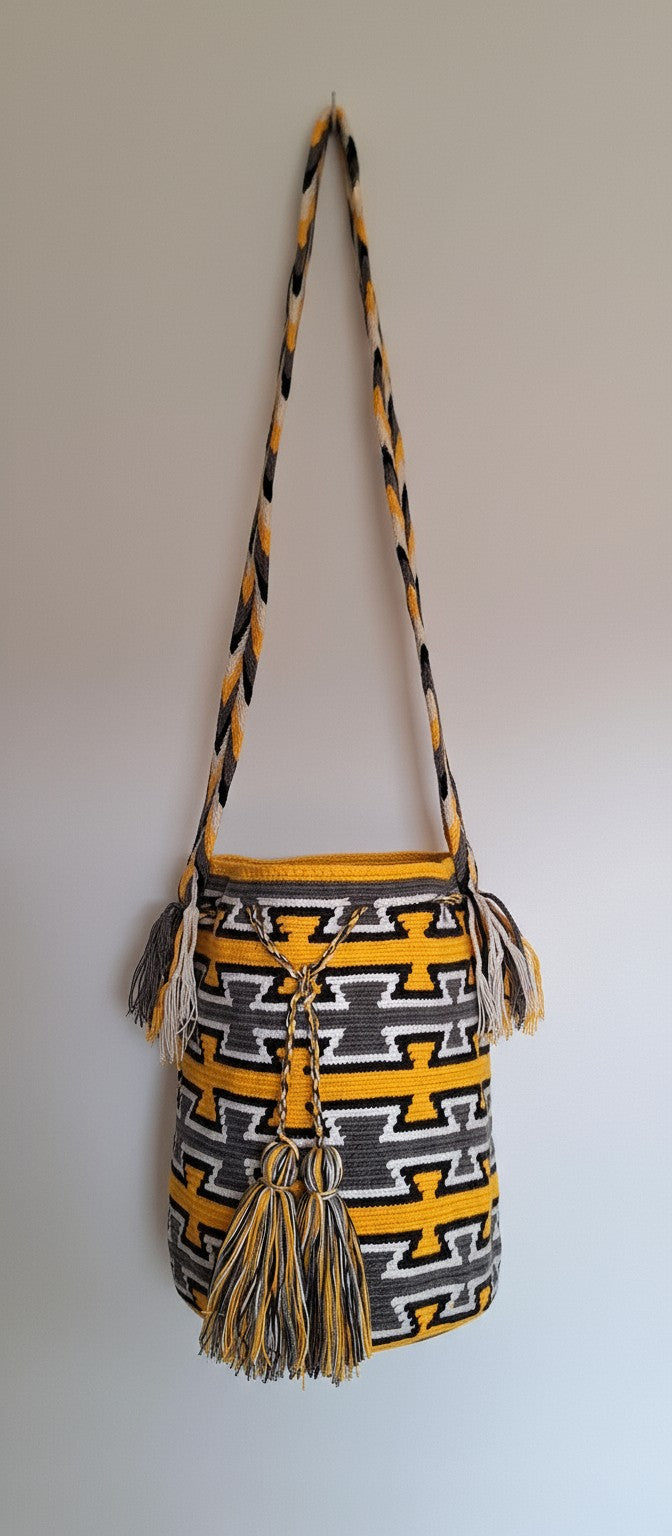 Detailed view of traditional Wayuu crochet technique and tassels on a yellow and grey mochila bag with crossbody strap fully extended. Ethically and responsibly sourced.
